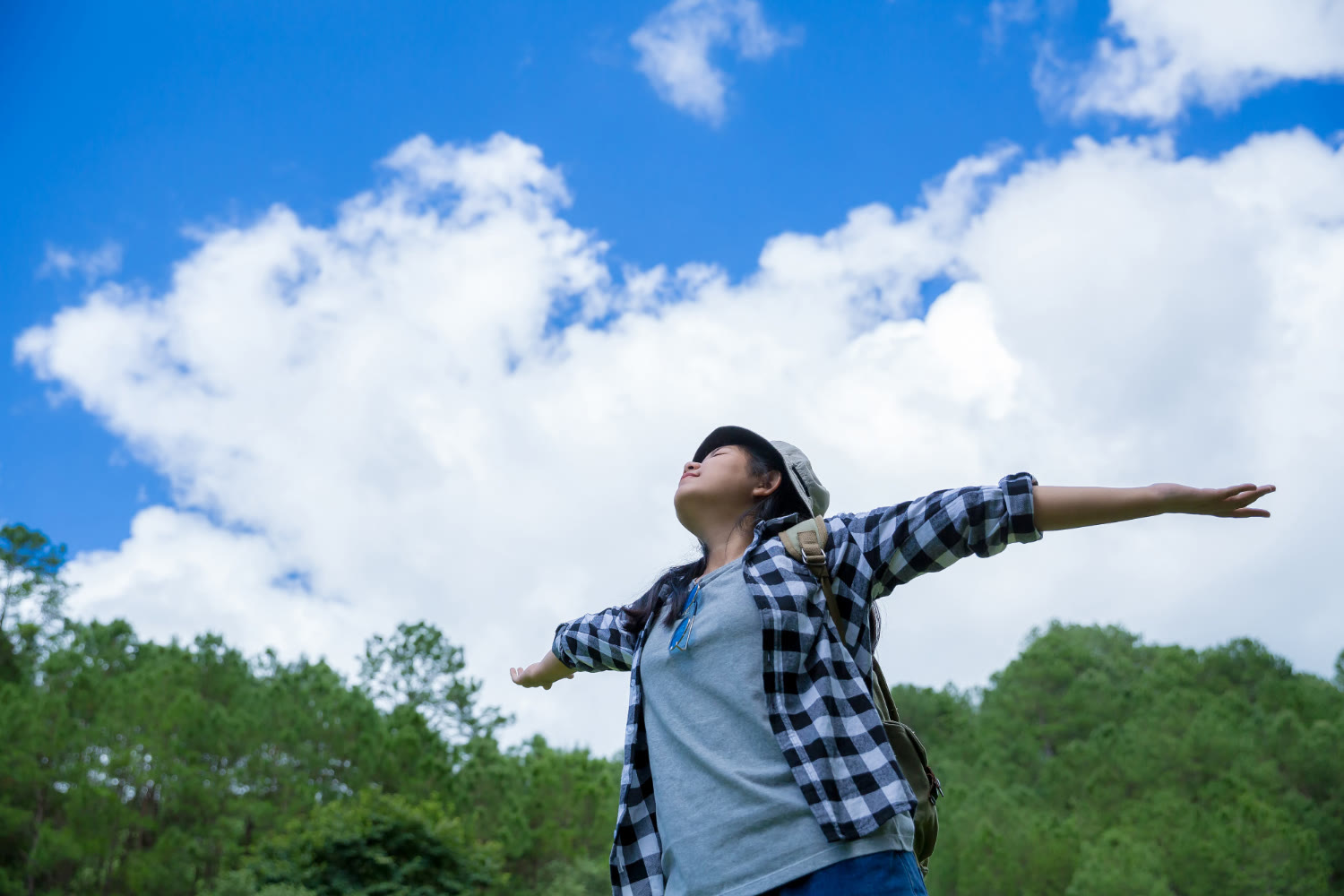 A young woman with her arms open wide under a blue sky